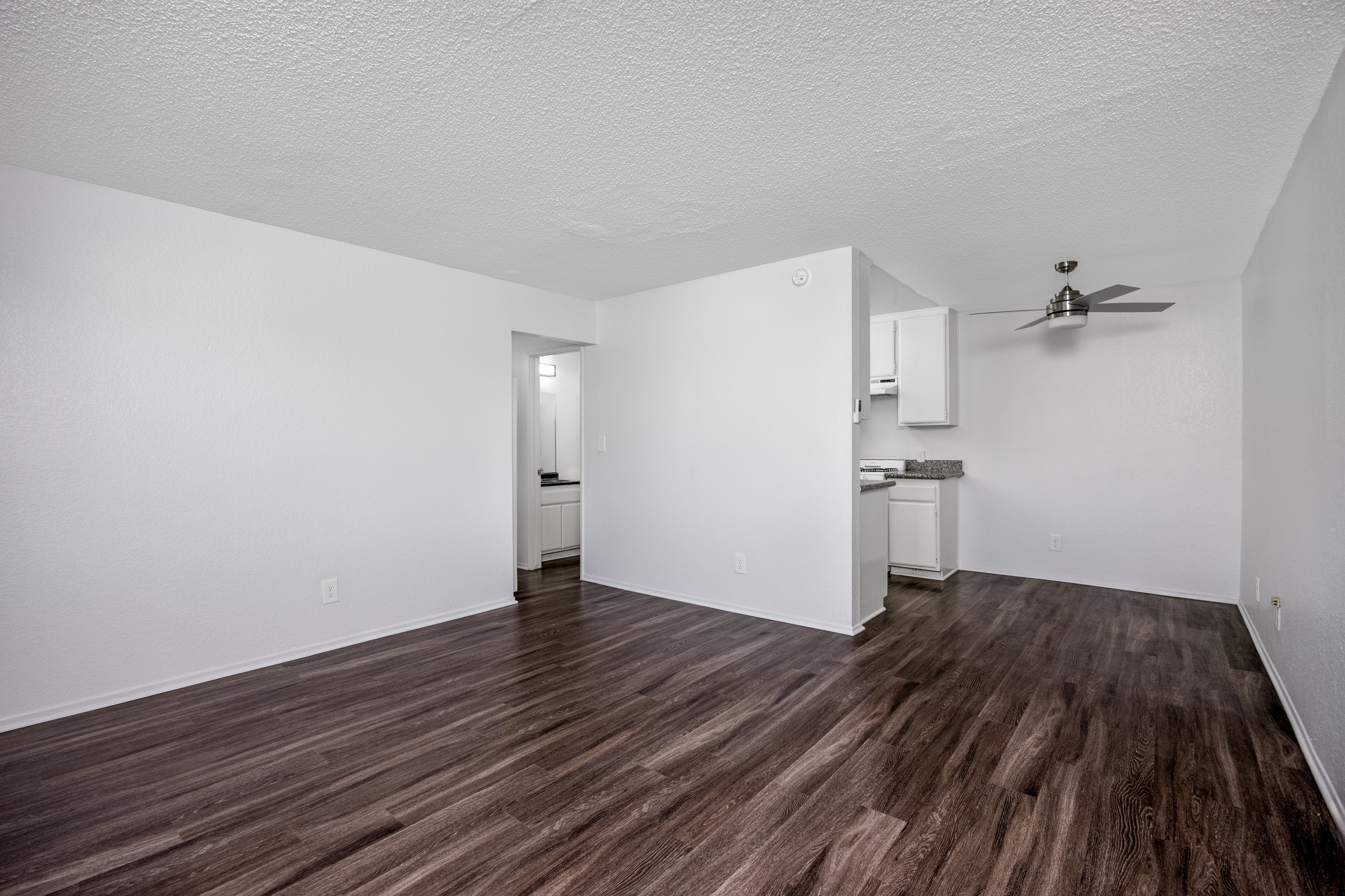 A room with wood flooring and a ceiling fan.
